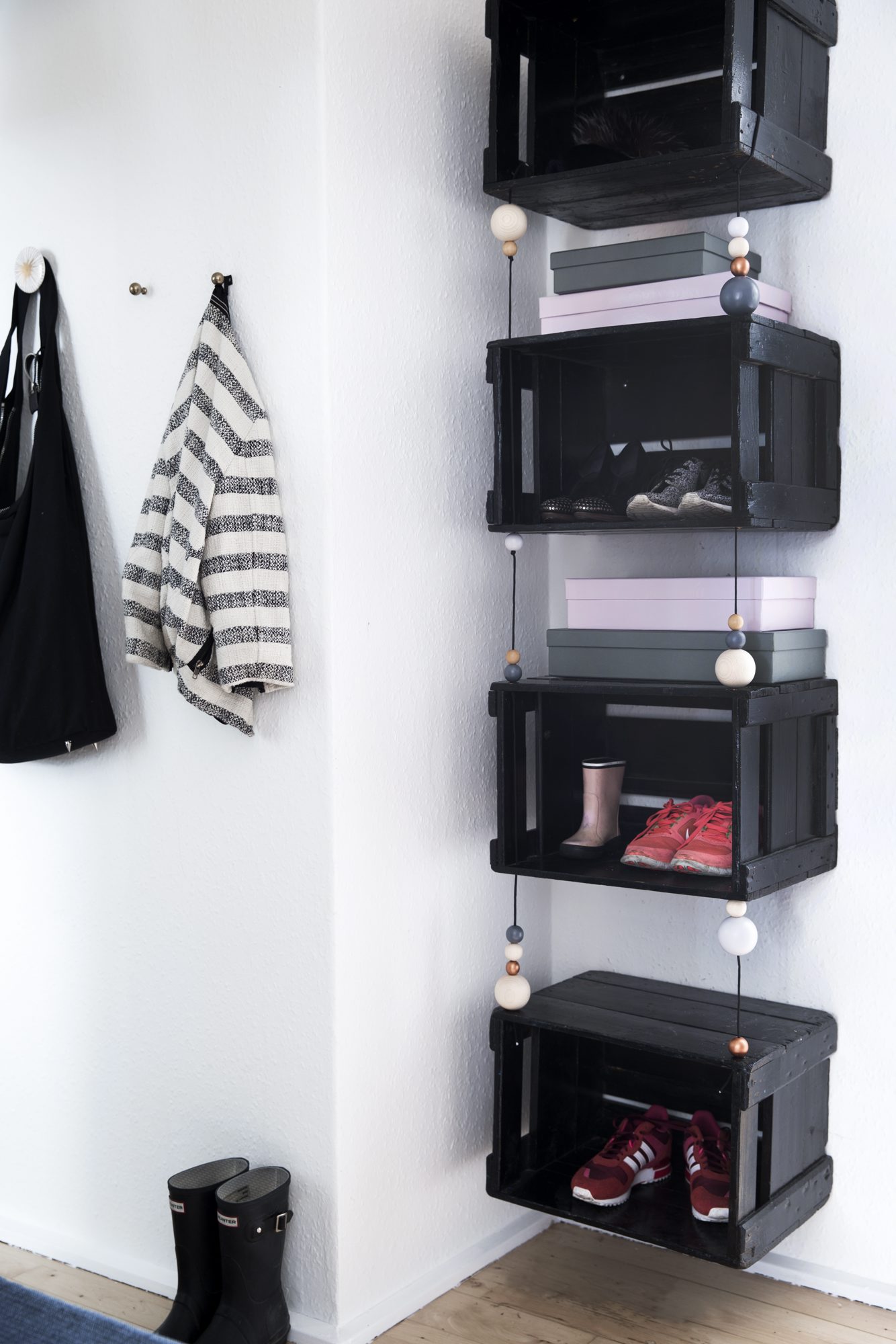 Ølkassene fungerer fint som skohyller. De er nå hengt opp med mellomrom sånn at beboerne får enda mer hylleplass, og kassene fikk en makeover med tråder og trekuler fra Panduro. FOTO: Tia Borgsmidt